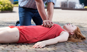 Moški na cesti nudi prvo pomoč dekletu z zastojem srca.