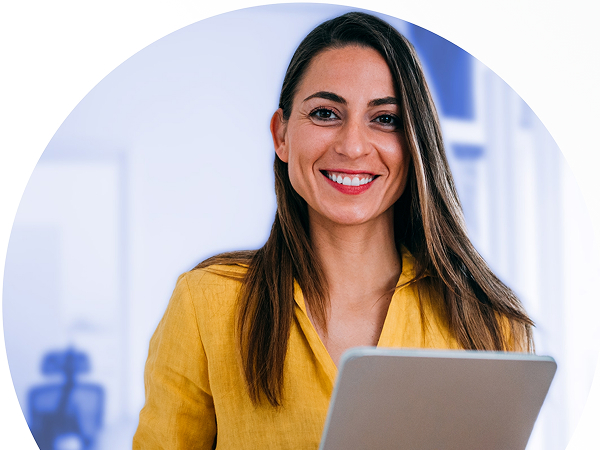 Smiling woman in a yellow shirt holding a tablet in an office setting