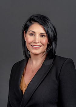 Headshot of Robyn Misiano, who smiles while wearing a burnt orange blouse and black blazer suit