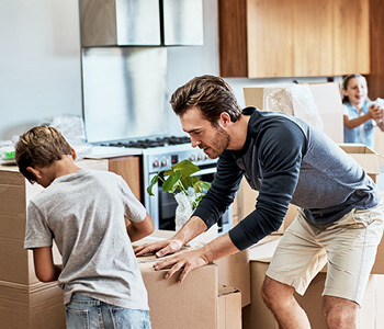 Družina med selitvijo prenaša škatle v novo stanovanje.