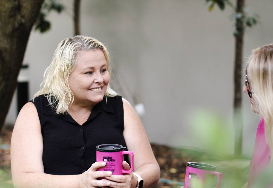 Close-up of Sharlene, a Mission Australia worker, smiling outdoors.