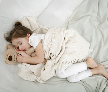 Spokojen trenutek za malčka, ki je zaspal v postelji, medtem ko je smrčanje pri otroku razlog za skrb staršev.