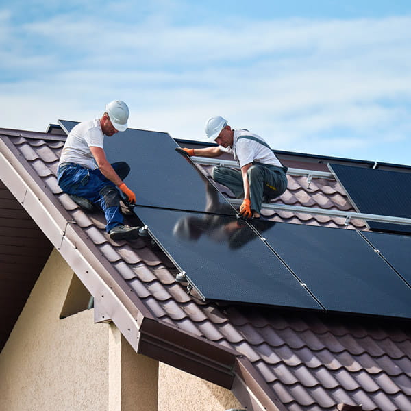 construction workers put solar panels on the roof of a house 