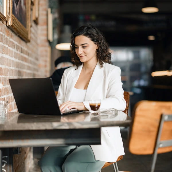 woman on her laptop at a cafe drinking an espresso