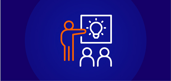 White line-art icon showing an orange figure pointing at a whiteboard with a bright lightbulb idea, standing in front of two white figures representing students, all on a dark blue background.