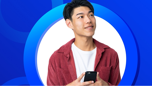 A smiling young man in a red corduroy shirt looks up and to the right while holding a smartphone, his head and shoulders framed by concentric blue rings on a white background.