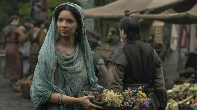 Tanzyn Crawford as Tanselle holding flowers in a market dressed in a blue head dress in A Knight of the Seven Kingdoms.