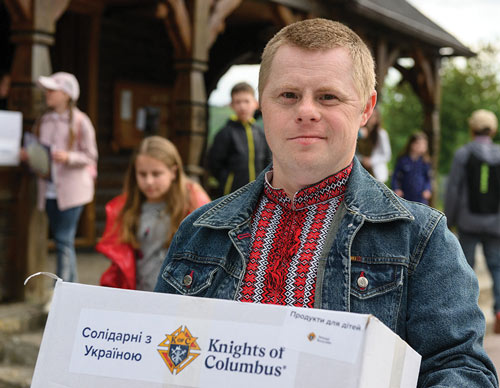A young Ukrainian man, families and children carry Knights of Columbus &ldquo;Solidarity with Ukraine&rdquo; packages they received