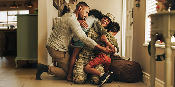 family hugging in their home welcoming their military mom