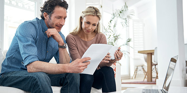 A white couple looks at paperwork together in their home