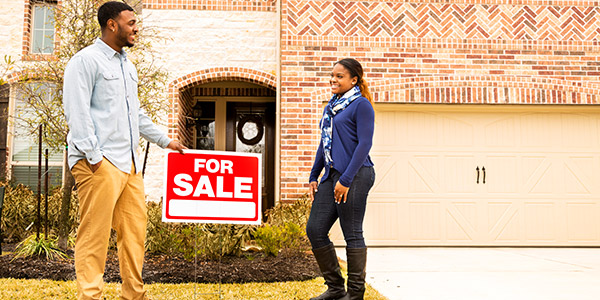 Borrower and real estate agent in from of a home with a for sale sign