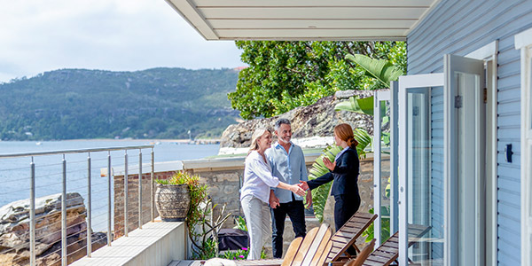 couple shaking hands with their real estate agent beofre viewing a coastal house