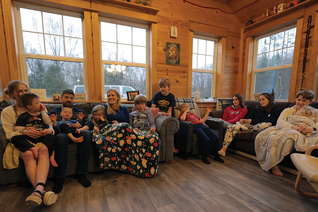 A family sitting on a couch at home praying together