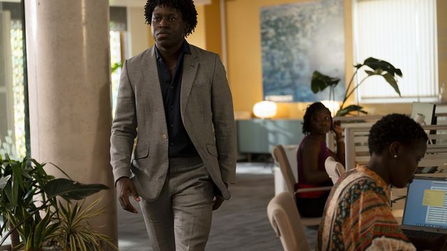 Kwabena Bannerman walks through an office wearing a gray suit