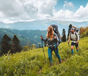 Mladi par je izbral trajnostni turizem in se z nahrbtnikom in pohodnimi palicami odpravil raziskovati hribe.
