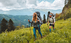 Mladi par je izbral trajnostni turizem in se z nahrbtnikom in pohodnimi palicami odpravil raziskovati hribe.