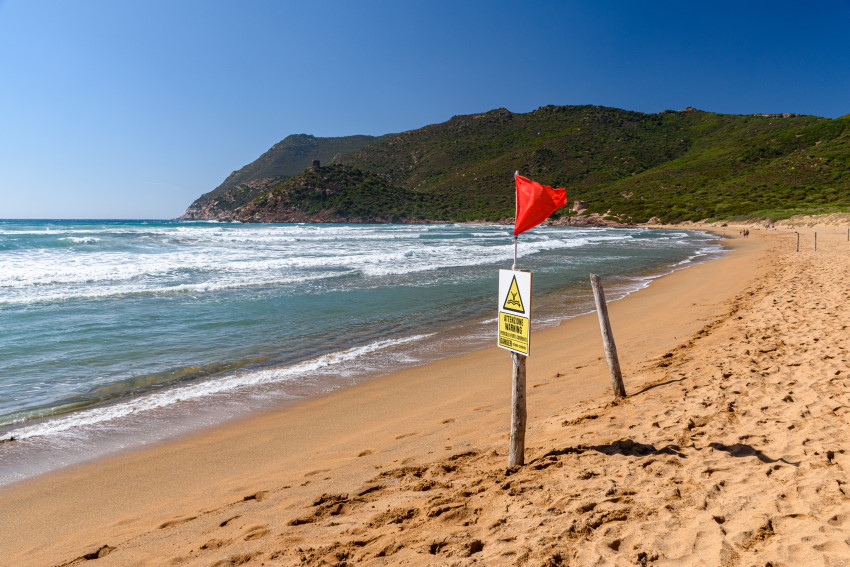 Rdeča zastava na plaži v Italiji opozarja na nevarnost kopanja zaradi razburkanega morja.