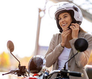 Ženska zapenja čelado za varn ovožnjo z mopedom - simbolna slika za zavarovanje motorja ali mopeda