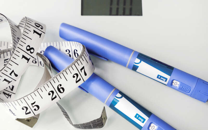 photo of scale, measuring tape and weight loss drugs to combat obesity