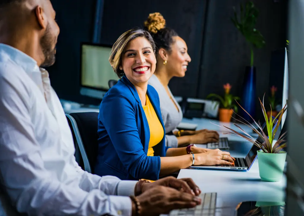 Smiling woman wearing blue smart jacket sitting at computer