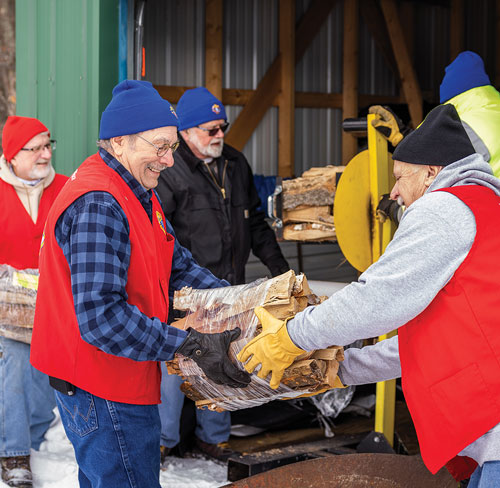 Five men outdoors carrying wood