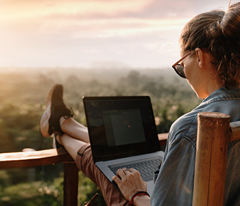 Dekle dela na računalniku na dopustu. Brez skrbi računalnik nosi s seboj na dopust, ker ga ščitijo močna gesla.