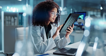 A female healthcare professional in a lab coat using a digital tablet in a modern laboratory environment