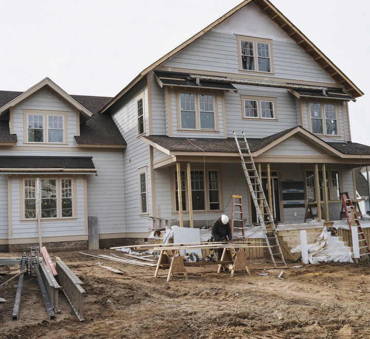 Contractors at a construction site, working on the exterior of a house.  