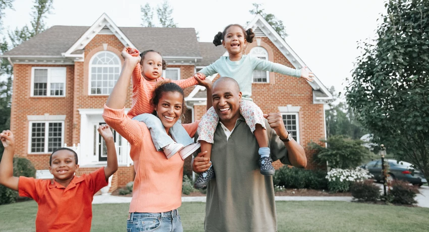 Family standing together outside a house, with the home visible in the background. 